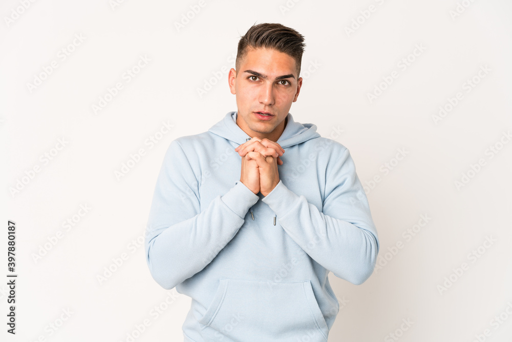 Young caucasian handsome man isolated praying for luck, amazed and opening mouth looking to front. Young caucasian handsome man isolated praying for luck, amazed and opening mouth looking to front.