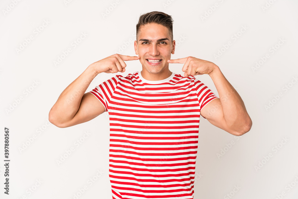 Young caucasian handsome man isolated smiles, pointing fingers at mouth. Young caucasian handsome man isolated smiles, pointing fingers at mouth.