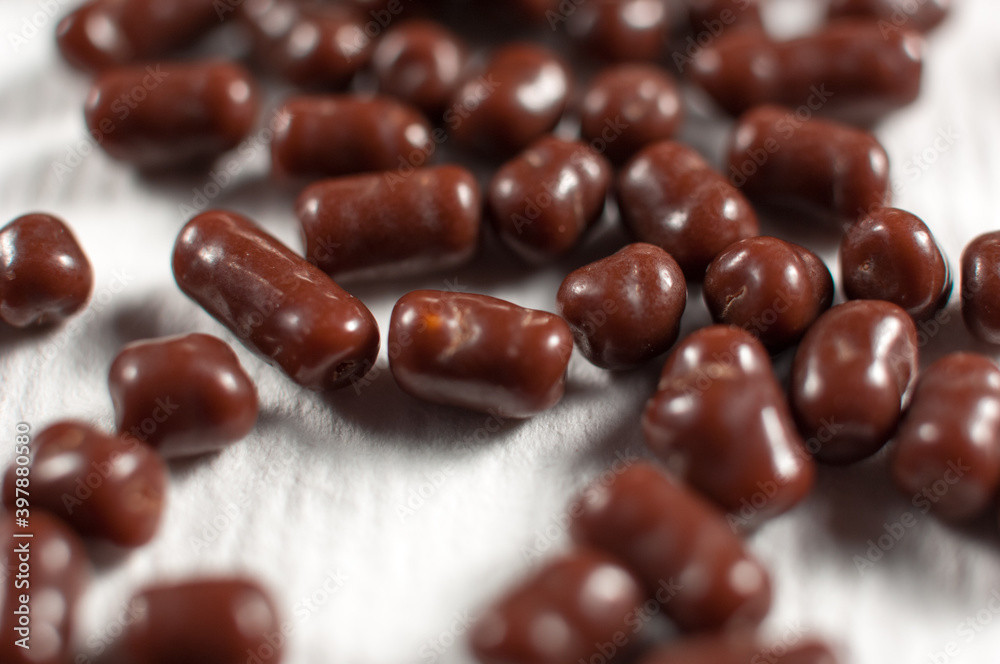 Chocolate dragee pile on white paper background Chocolate dragee pile on white paper background
