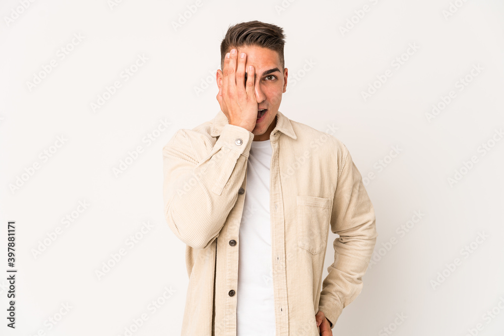 Young caucasian handsome man isolated having fun covering half of face with palm. Young caucasian handsome man isolated having fun covering half of face with palm.