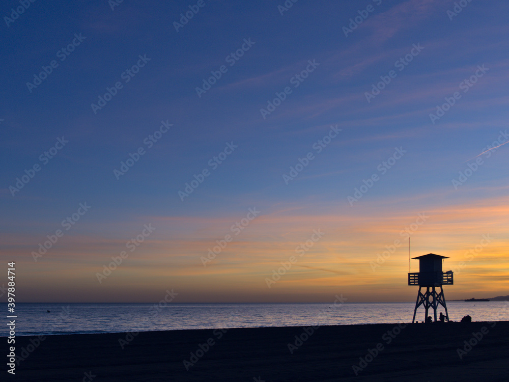 Silhouette at sunset of a guard post on the beach. Lifeguard tower on the coast