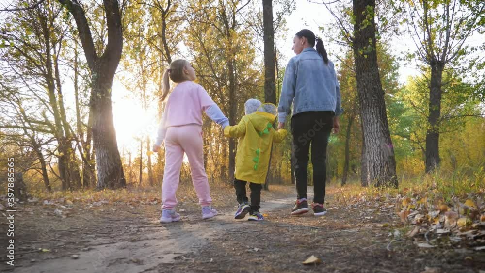 Mother and two children walking in the park and enjoying the beautiful autumn nature. Happy family on autumn walk. Mother and two children walking in the park and enjoying the beautiful autumn nature. Happy family on autumn walk.