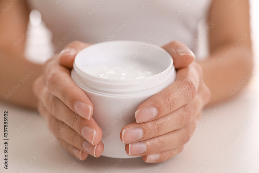 Woman with jar of moisturizing cream at white table, closeup Woman with jar of moisturizing cream at white table, closeup