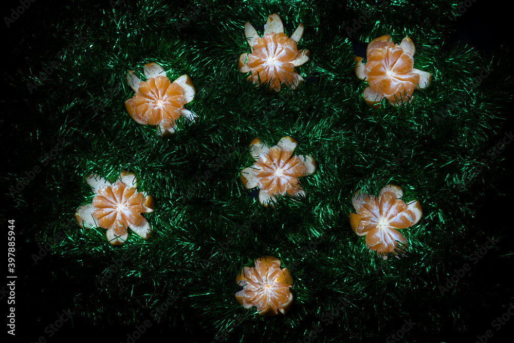 Peeled fresh bright mandarin amidst green and shimmering tinsel. Peeled fresh bright mandarin amidst green and shimmering tinsel.