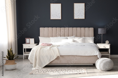Comfortable bed with soft blanket in stylish room interior photo