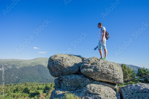 Man in sportswear on a big rock seeing the green valley on a sunny day