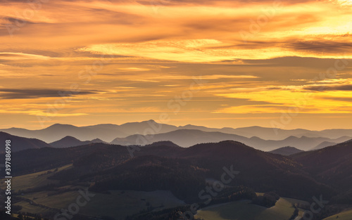 Mountains colored in shades of orange at sunset in autumn..The ridges of the mountains are condensed from the perspective of a telephoto lens.