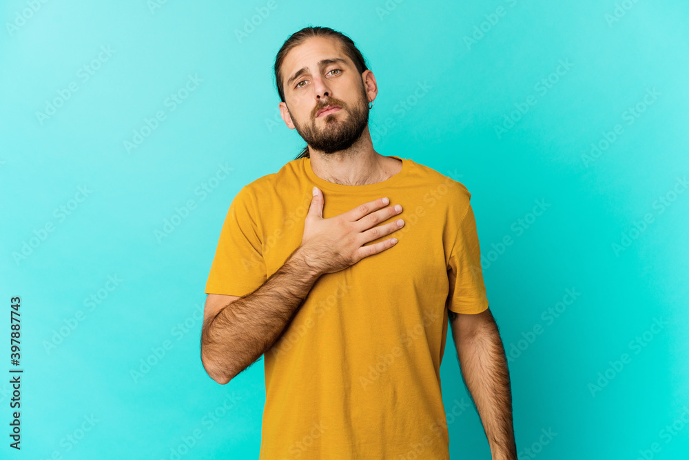 Young man with long hair look taking an oath, putting hand on chest.