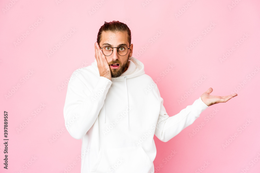 Young man with long hair look impressed holding copy space on palm. Young man with long hair look impressed holding copy space on palm.