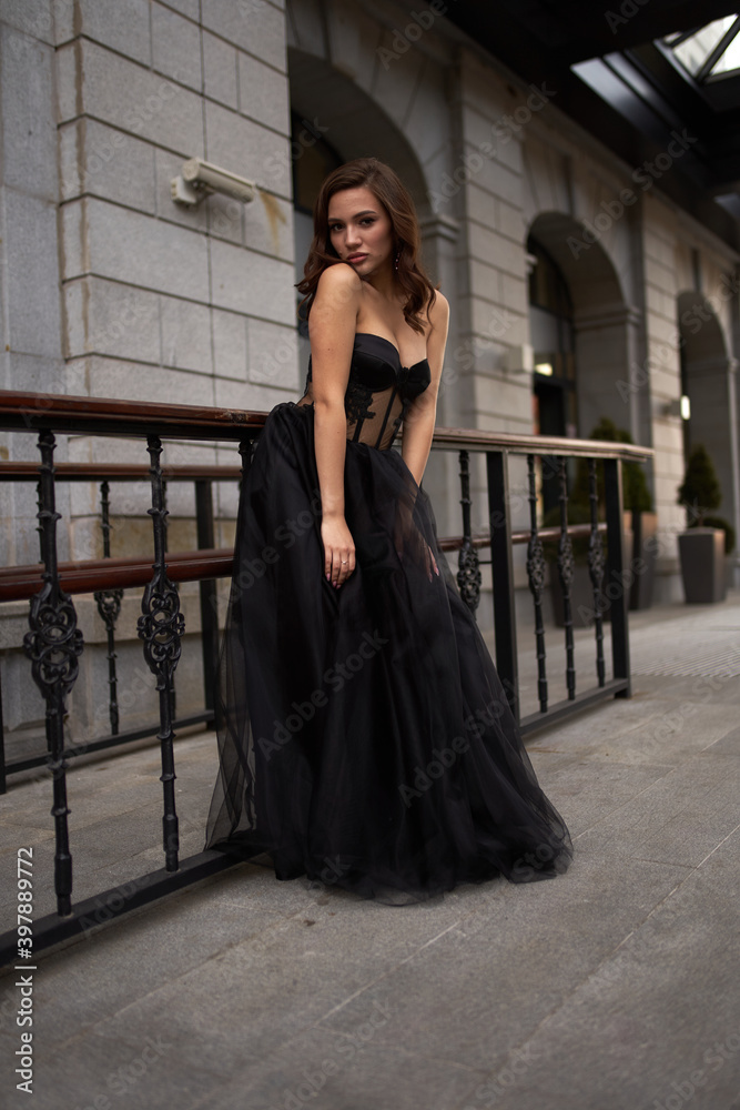 Full-length portrait of an elegant brunette woman with long hair in a black long evening dress. Full-length portrait of an elegant brunette woman with long hair in a black long evening dress.