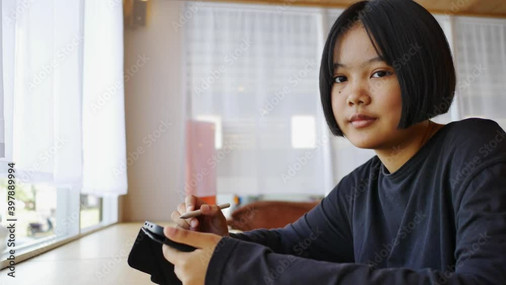 Asian teenager to use tablet drawing and ding homework in living room Asian teenager to use tablet drawing and ding homework in living room