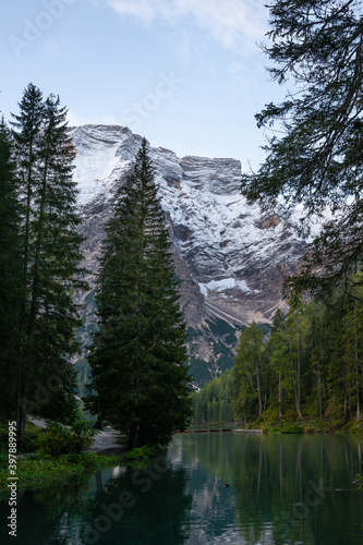 A vertical view of the lake Pragser Wildsee in the Dolomites with a chain of boats, mountains and woods in autumn in South Tyrol, Italy.