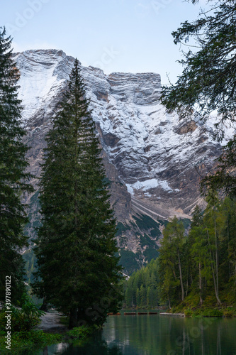 A vertical view of the lake Pragser Wildsee in the Dolomites with a chain of boats, mountains and woods in autumn in South Tyrol, Italy.