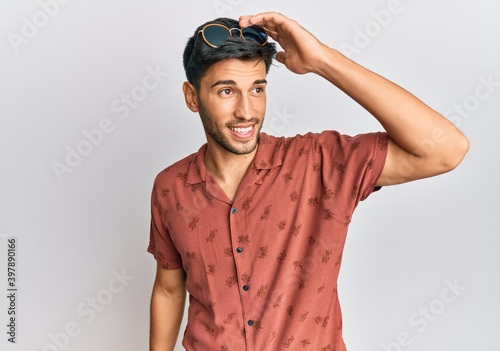 Young handsome man wearing casual summer clothes smiling confident touching hair with hand up gesture, posing attractive and fashionable
