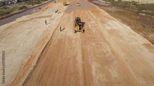 Aerial view of heavy machinery, motor grader spreader gravel in preparation for road construction. heavy equipment top down footage
