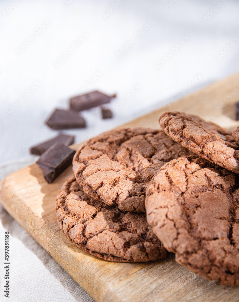 homemade chocolate cookies with chocolate chips on wood cutting board on a light table homemade chocolate cookies with chocolate chips on wood cutting board on a light table