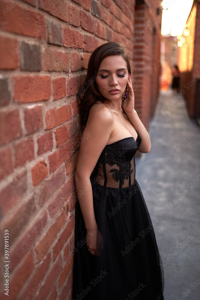 Full-length portrait of an elegant brunette woman with long hair in a black long evening dress. Full-length portrait of an elegant brunette woman with long hair in a black long evening dress.