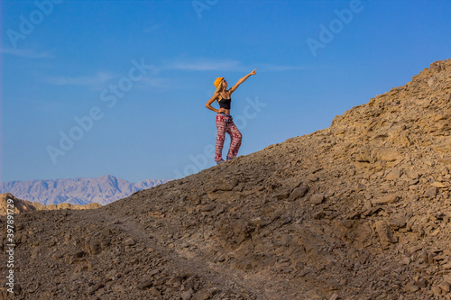 travel tourism life style concept advertising wallpaper photography of posing model girl on sand stone hill in Middle East region summer clear weather day time
