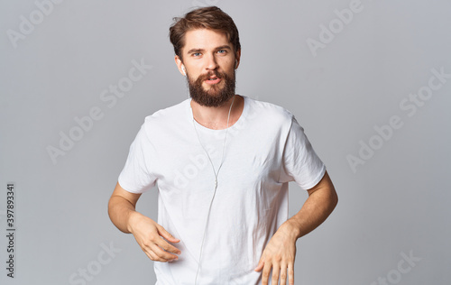 man in headphones dancing on a gray background and listening to music