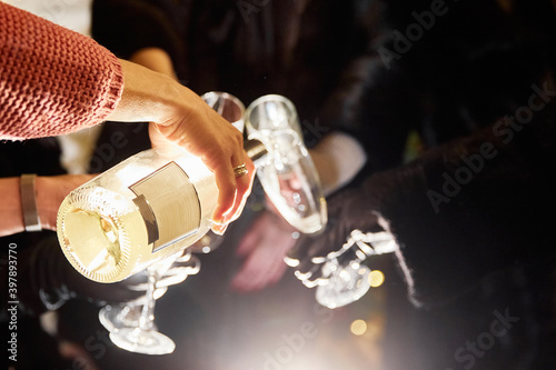 New Year's atmosphere 2021. Girls pouring champagne into glasses. Beautiful bokeh