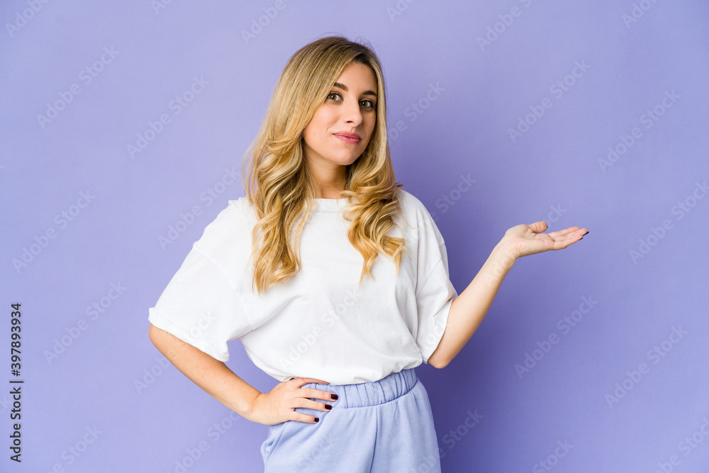 Young caucasian blonde woman showing a copy space on a palm and holding another hand on waist. Young caucasian blonde woman showing a copy space on a palm and holding another hand on waist.