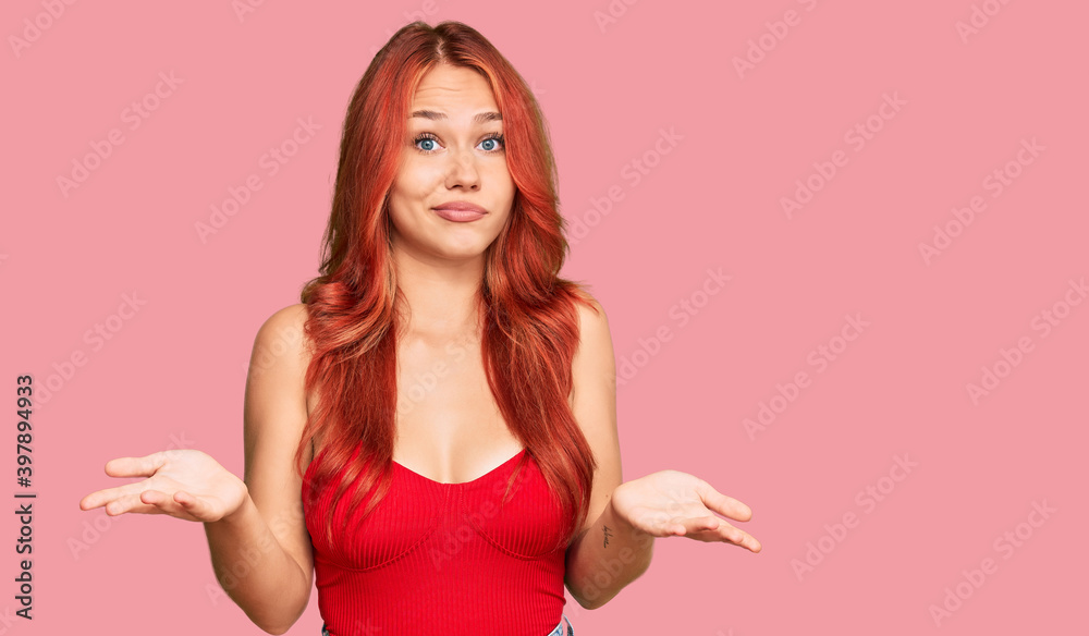 Young redhead woman wearing casual clothes clueless and confused expression with arms and hands raised. doubt concept. Young redhead woman wearing casual clothes clueless and confused expression with arms and hands raised. doubt concept.