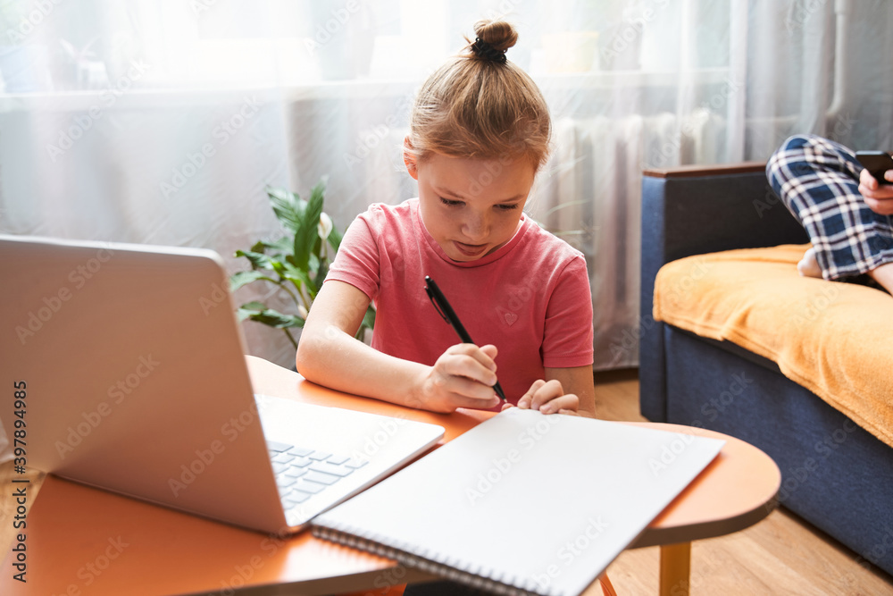 Kid sitting at the table and working with her laptop Kid sitting at the table and working with her laptop