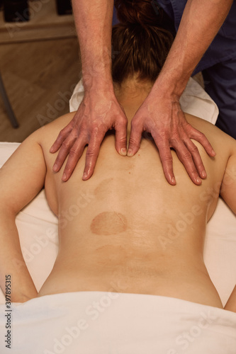 masseur making back massage to his client. elements of wellness massage and body relaxation. Chiropractor does rehabilitation procedure on trapezius and infraspinatus muscle. Selective focus.