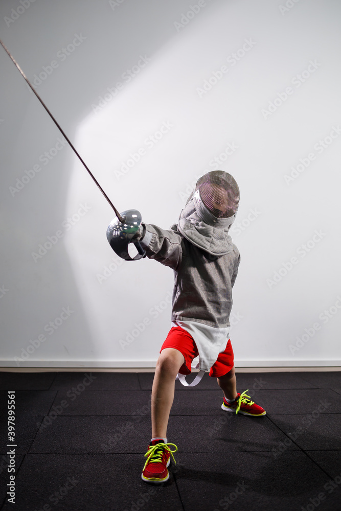 Foto de A child in a fencing costume is holding an epee. Girl learning