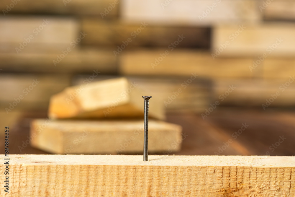 Close-up of a single nail stuck in a wooden board