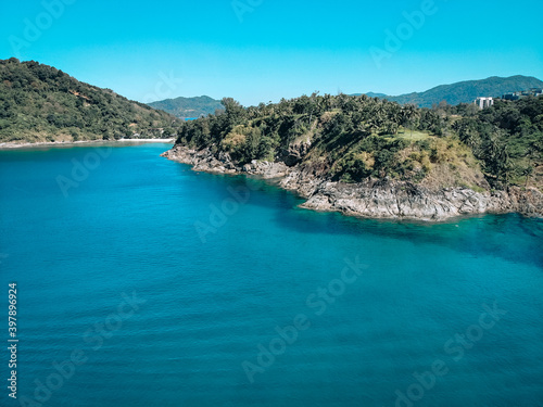 Top view of the beautiful coast of an isolated island around which clear blue water with inspiring waves © Semachkovsky 