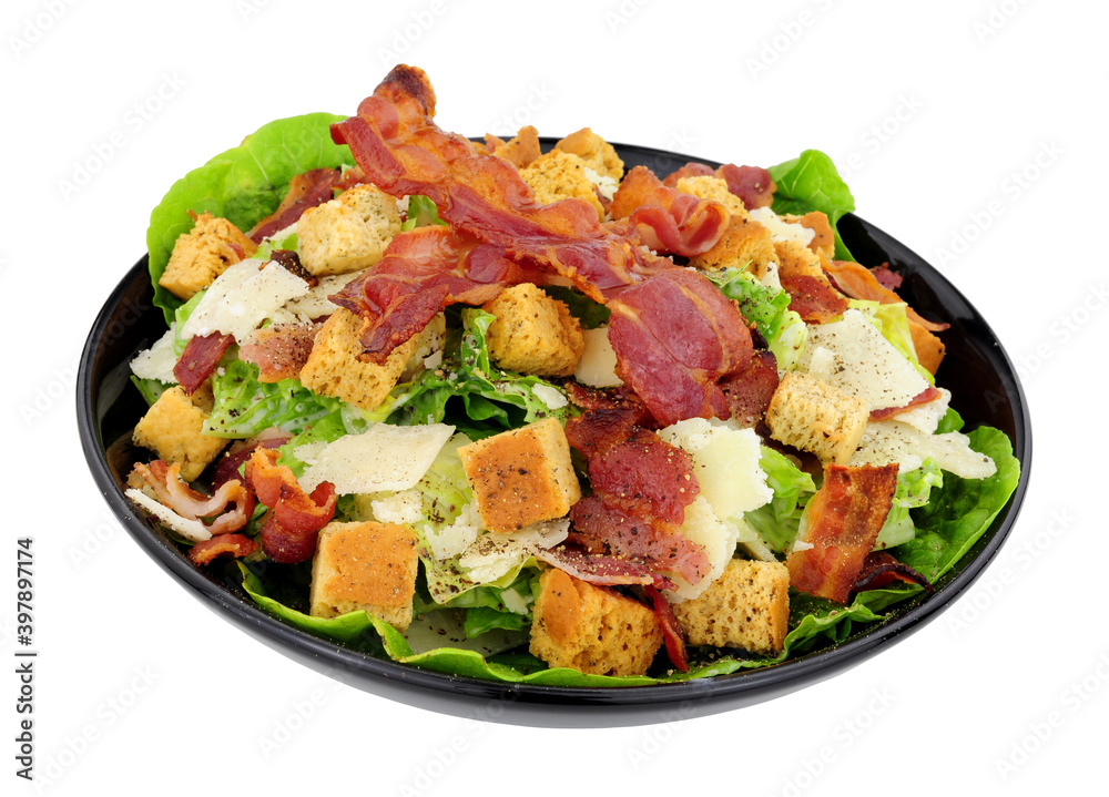 Bacon Caesar salad with romaine lettuce and parmesen cheese shavings served in a black dish isolated on a white background Bacon Caesar salad with romaine lettuce and parmesen cheese shavings served in a black dish isolated on a white background