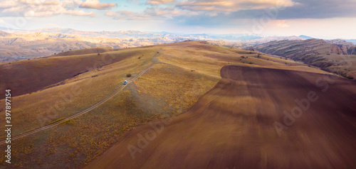 Aerial scenic view of Vashlovani national park protected area landscape with jeep on the road passig in the foreground photo