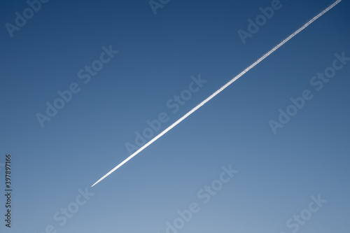 White condensation trace of jet airplane in deep blue sky