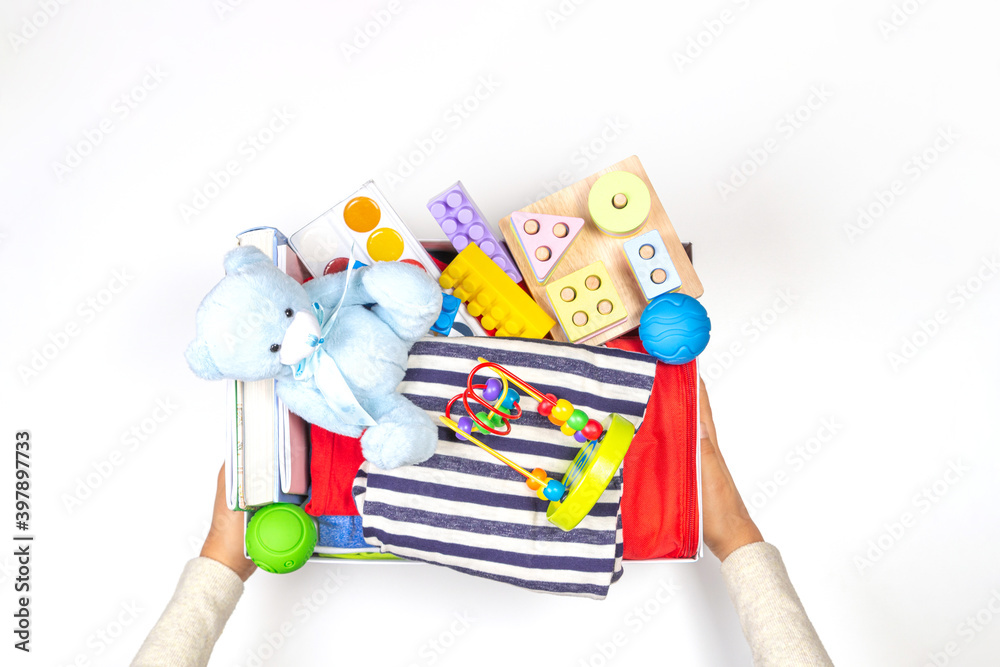Naklejka premium Donation charity concept. Hands holding donate box with clothes, books, school supplies and toys on white background