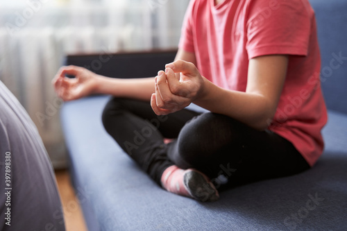 Girl sitting on sofa in lotus positions