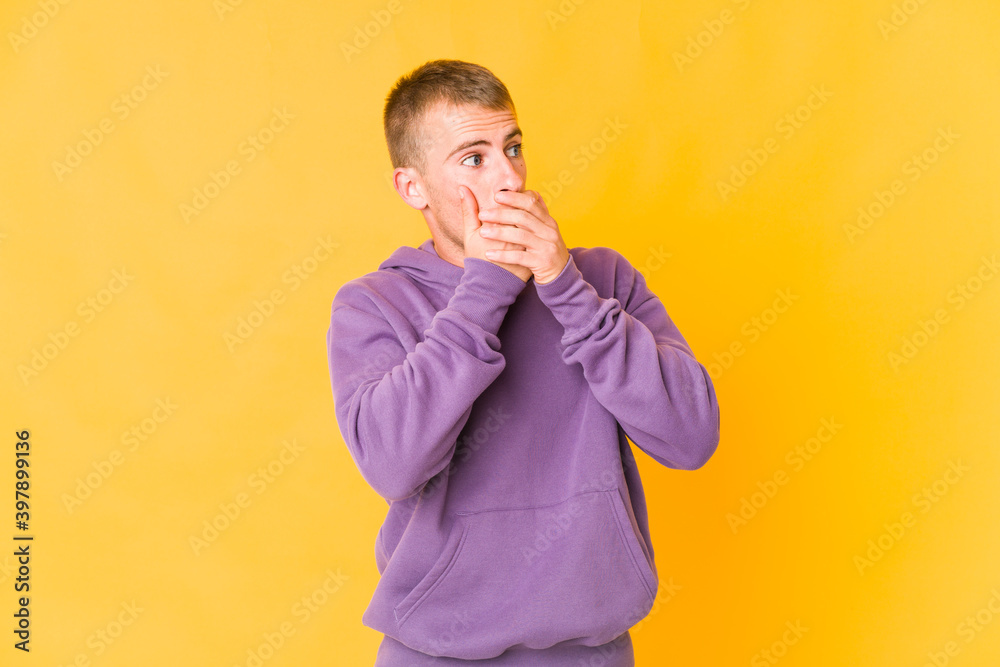 Young caucasian handsome man thoughtful looking to a copy space covering mouth with hand. Young caucasian handsome man thoughtful looking to a copy space covering mouth with hand.