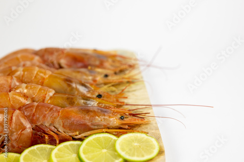 prawns on a wooden cutting board with pieces of lime
