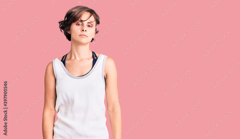 Beautiful young woman with short hair wearing casual sport clothes with serious expression on face. simple and natural looking at the camera. Beautiful young woman with short hair wearing casual sport clothes with serious expression on face. simple and natural looking at the camera.