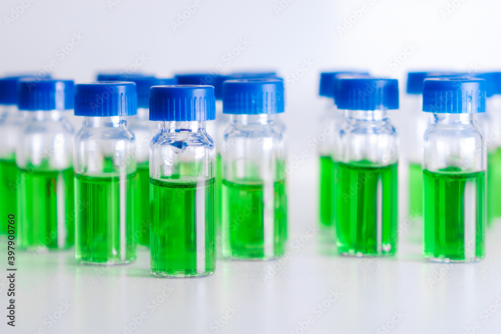 HPLC vials with green sample of plant extracts. Developing of drugs based on natural products. Biochemical analysis HPLC vials with green sample of plant extracts. Developing of drugs based on natural products. Biochemical analysis