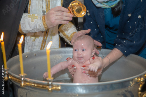 Vászonkép Baby baptised in baptism bowl in church