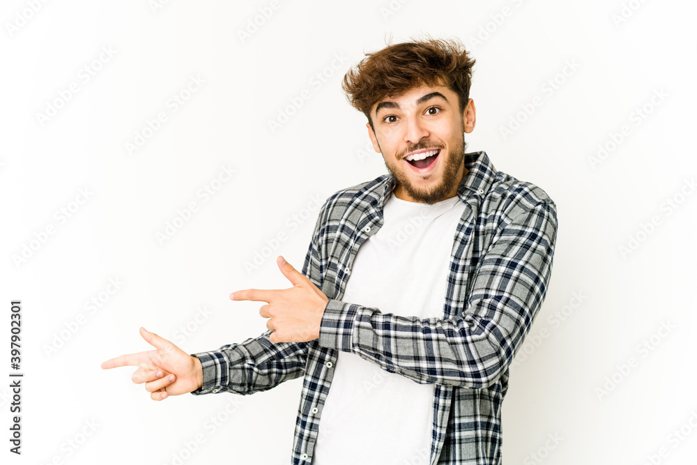 Young arab man on white background excited pointing with forefingers away. Young arab man on white background excited pointing with forefingers away.