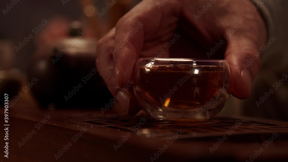 The hospitable host treats the guest to delicious Japanese tea from a glass bowl. Close-up without a face.