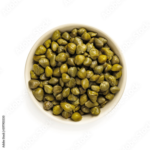 Pickled capers in a beige bowl isolated on white background. Marinated buds of caper bush. Mediterranean cuisine ingredient. Organic spices and seasonings for meat, fish and vegetables.