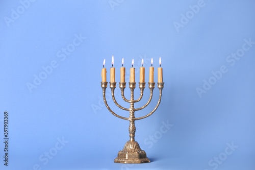 Golden menorah with burning candles on light blue background, space for text photo