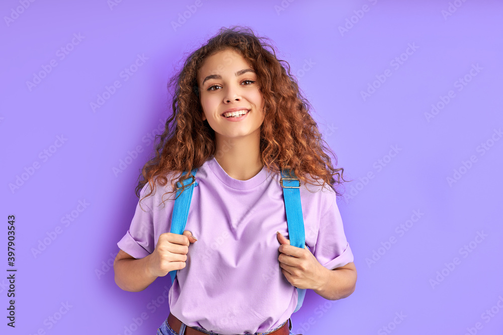 positive school girl with bag posing at camera isolated over purple background, cheerful female with curly hair smile, happy to go school. education concept positive school girl with bag posing at camera isolated over purple background, cheerful female with curly hair smile, happy to go school. education concept