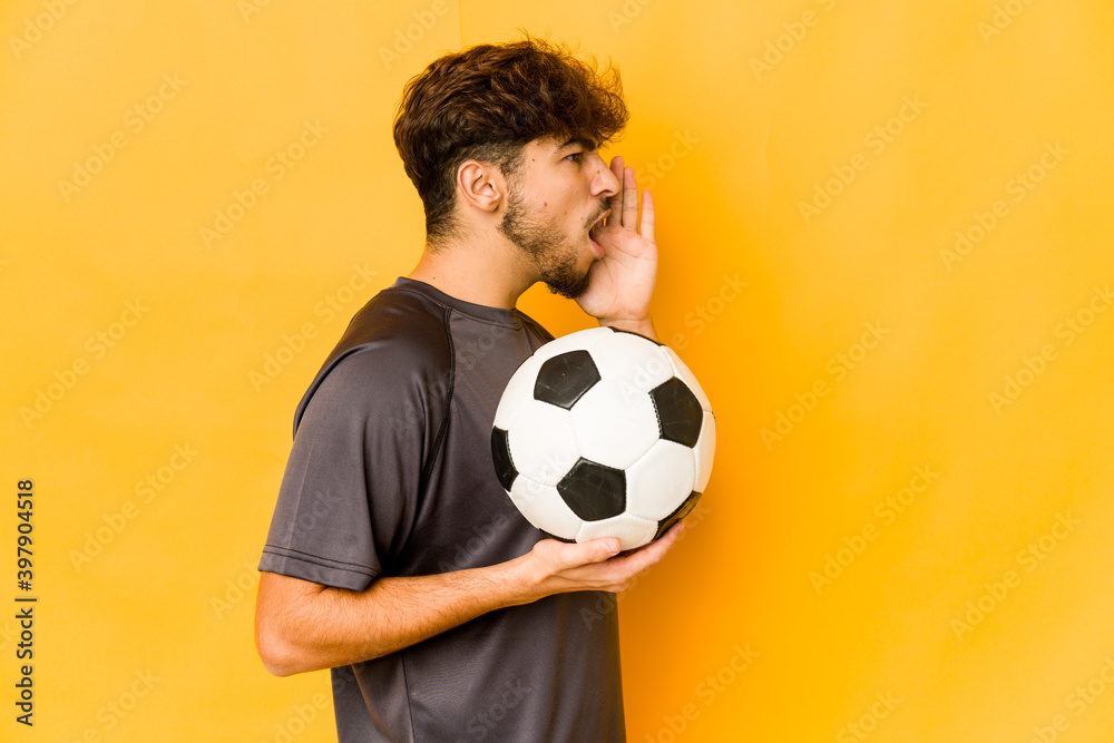 Young soccer player indian man shouting and holding palm near opened mouth. Young soccer player indian man shouting and holding palm near opened mouth.