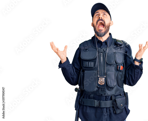 Young handsome man wearing police uniform crazy and mad shouting and yelling with aggressive expression and arms raised. frustration concept.
