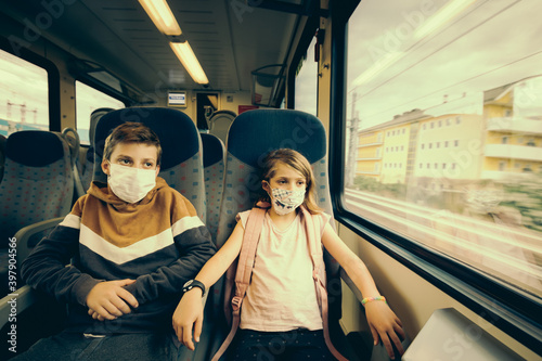 Deux jeunes enfants partant en voyage en vacances en train avec des masques contre la covid-19 photo