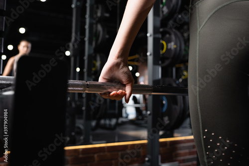 partial view of sportswoman working out with power rack in gym